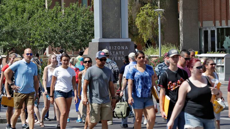 ARCHIVO - Transeúntes caminan en el campus de la Universidad Estatal de Arizona en Tempe,...