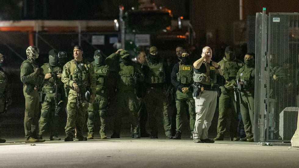 Federal law enforcement officers stand guard in the open gate of the fence built on Beach...