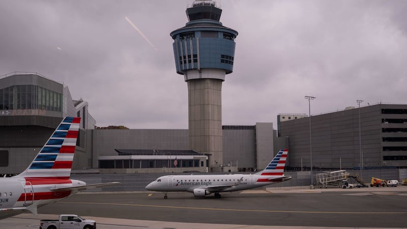 Un avión de American Eagle pasa junto a la torre de control de tráfico aéreo en el Aeropuerto...