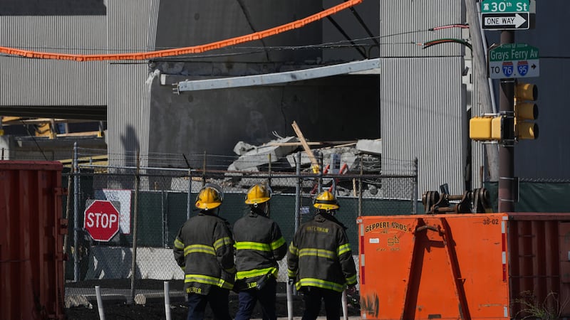 Personal de emergencia camina cerca de un estacionamiento parcialmente derrumbado en...